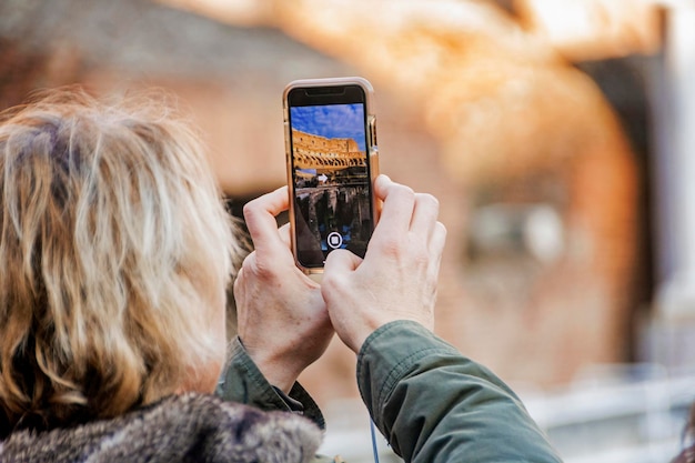 Hand holding smartphone taking picture in Colosseum stadium building in Rome