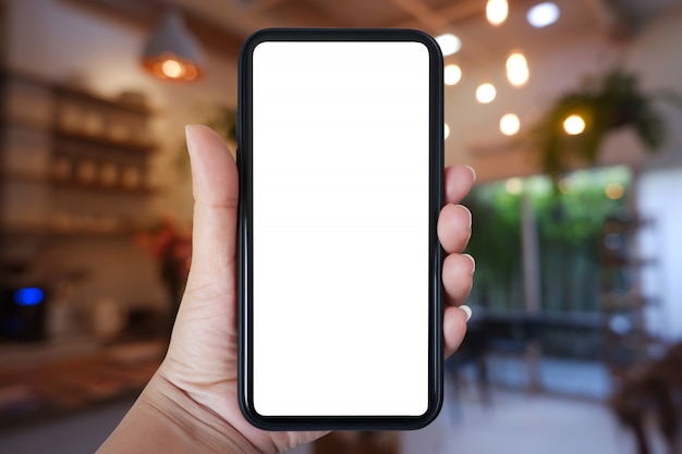 Hand holding smartphone with blank screen for app on cafe interior