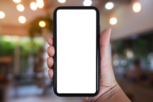 Hand holding smartphone with blank screen for app on cafe interior