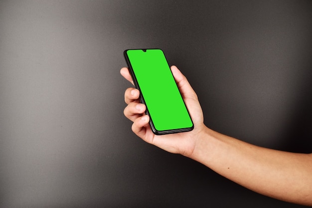 Hand holding a smartphone with green screen