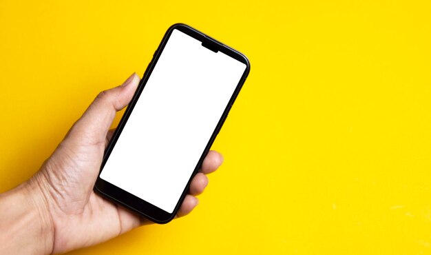 Hand holding a smartphone on a yellow background