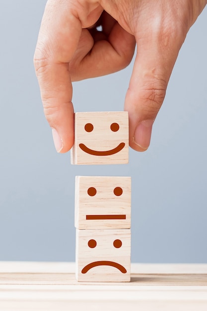 hand holding smile face symbol on wooden blocks