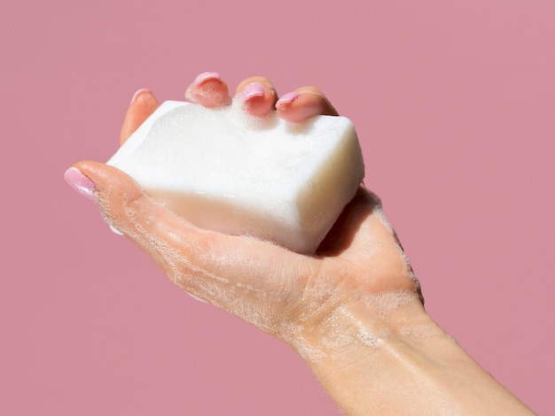 Photo hand holding soap bar with foam