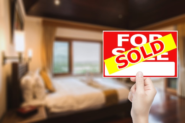 Photo hand holding sold house sign