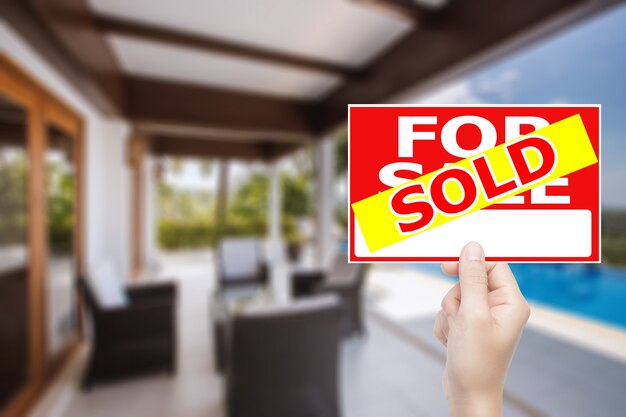 Hand holding sold house sign