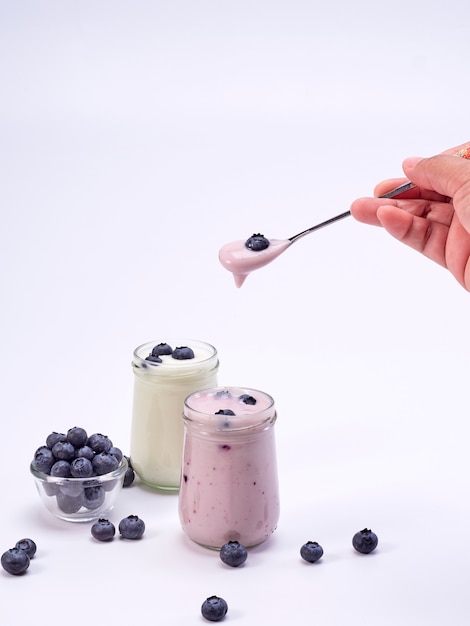 hand holding a spoon with blueberry yogurt