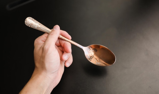 A hand holding a spoon with the word copper on it