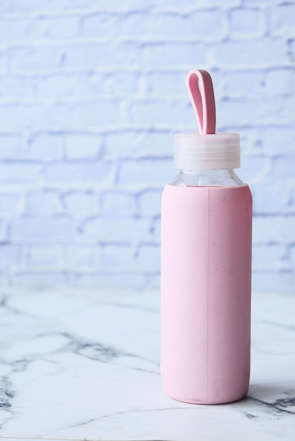 Hand holding sport bottle isolated on pink, top view