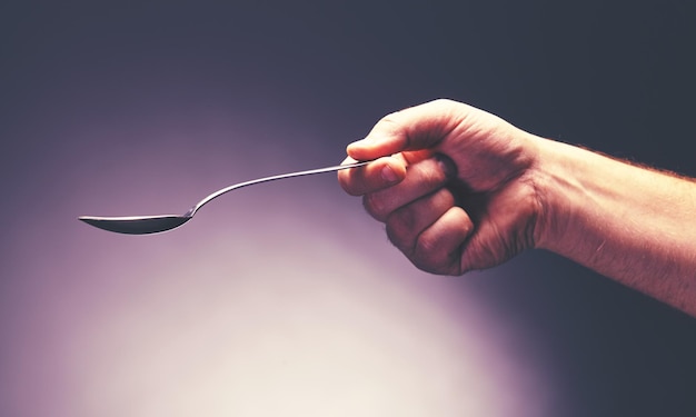 A hand holding a stainless steel spoon