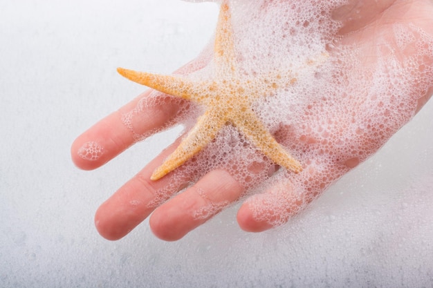 Hand holding starfish in foamy water