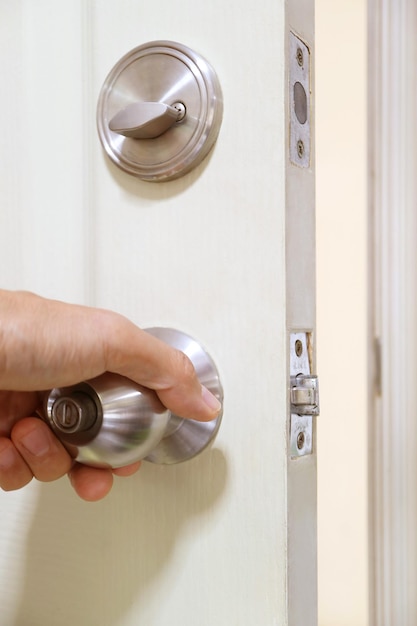 Hand holding steel doorknob for closing the door