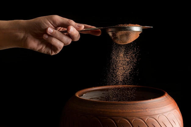 Hand holding strainer with cocoa powder