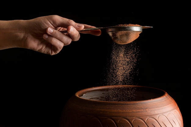 Photo hand holding strainer with cocoa powder