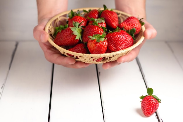 Hand holding a strawberry on a bascket on white background Close up