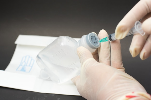 Hand holding syringe and vaccine.