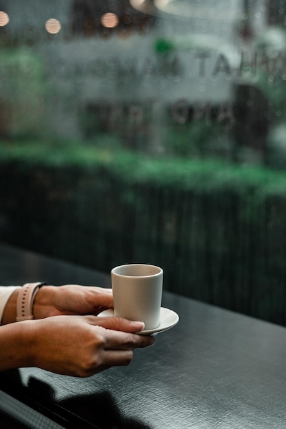 hand holding a take-out coffee on black table