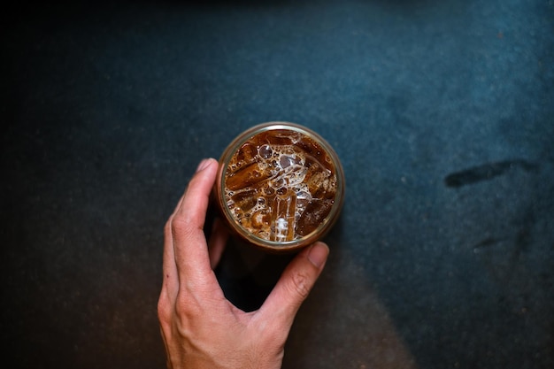 hand holding a take-out iced coffee on black table