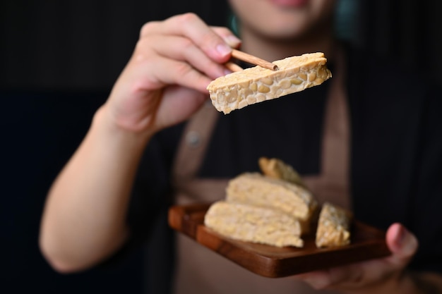 Hand holding Tempeh with bamboo chopsticks Vegan appetizers traditional Indonesian soy product