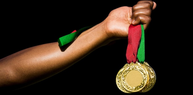 Hand holding three gold medals on white background