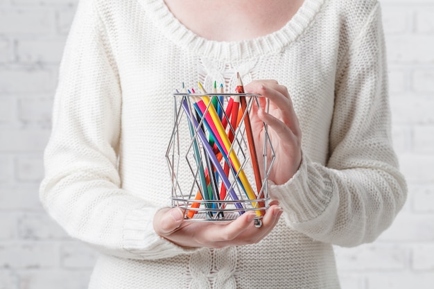 Hand holding a tin with color pencils