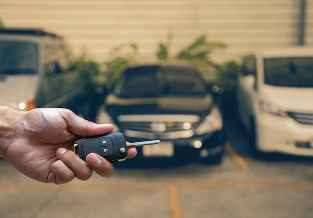 Hand holding and touching the keys over photo blurred of used car