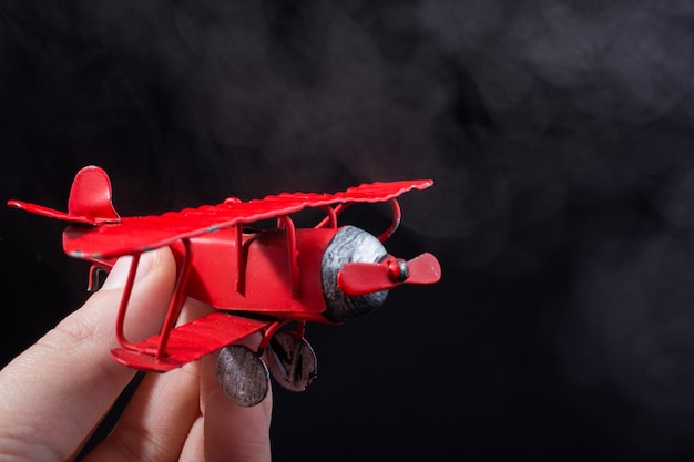 Hand holding a toy plane on black background