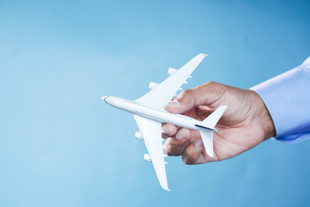 Hand holding toy plane over blue background