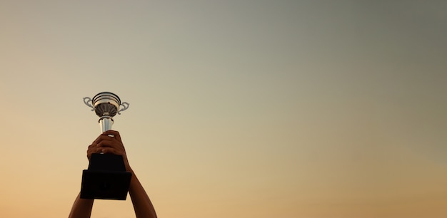 Foto mano che tiene un trofeo sul tramonto