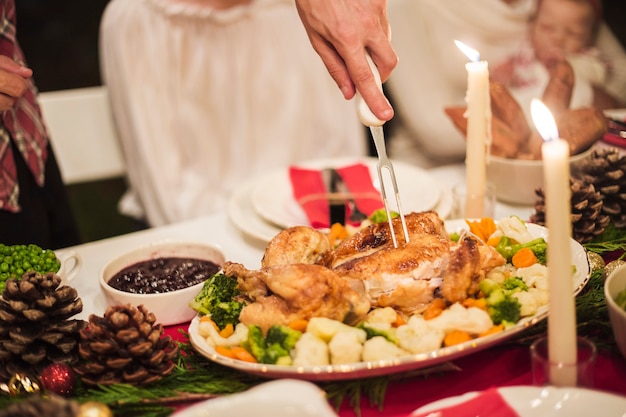 Mano che tiene la turchia con la forchetta al tavolo di natale