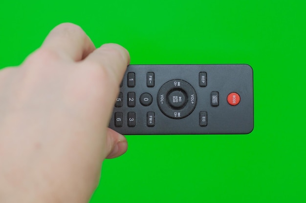 사진 초록색 배경 위의 tv 리모컨을 손으로 들고 있는  뷰