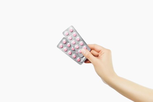 hand holding two blisters with pink pills on a white background