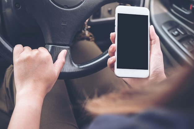 Foto una mano che tiene e utilizza il telefono con lo schermo del desktop nero bianco durante la guida