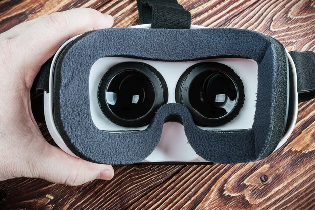 Hand holding virtual glasses on a wooden background