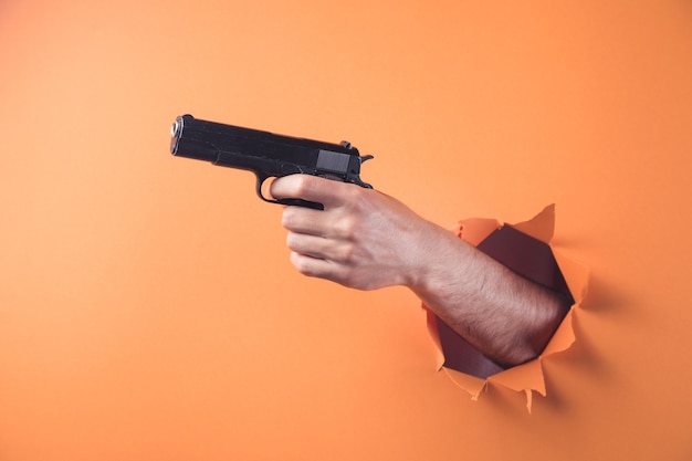 Hand holding a weapon on orange background