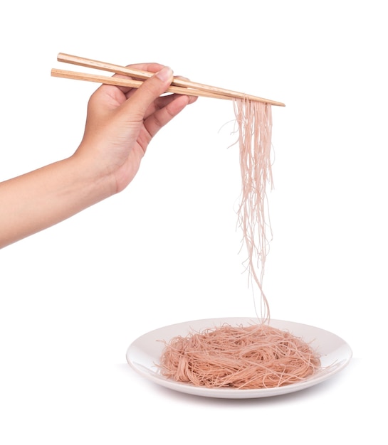 Hand holding wheat thin noodles by chopsticks on a dishl isolated on white background