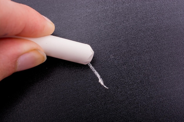 Hand holding white chalk and black board