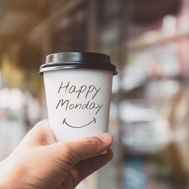 Foto mano che tiene tazza di carta caffè bianco con testo