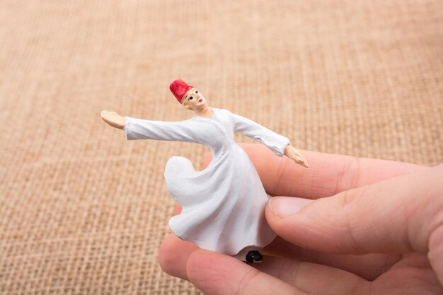 Photo hand holding a white color sufi dervish figurine in hand