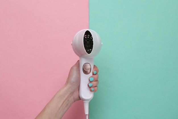 Photo hand holding white hair dryer on pink blue background beauty concept hair care hair style top view flat lay