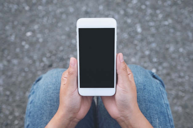 Рука держит белый мобильный телефон с пустым черным экраном