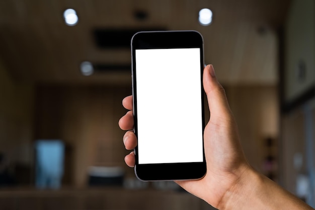 Hand holding white mobile phone with blank white screen in\
cafe