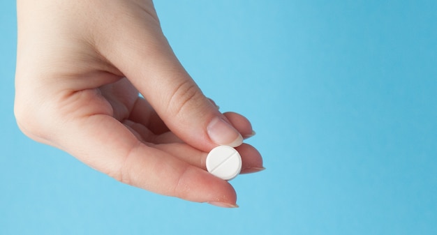 Hand holding a white pill