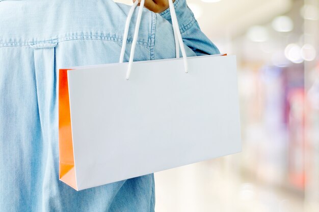 Photo hand holding white shopping bag on blur store background with copy space for text, template, business concept