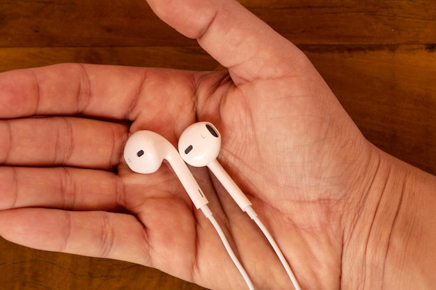 Hand holding white wired headphones