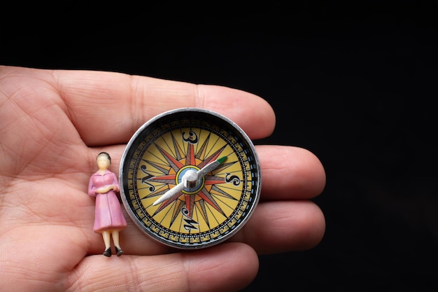 Hand holding woman figurine by compass as a concept of traveling