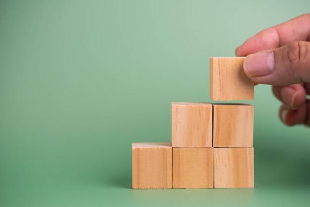 Hand holding wood cube block blank on green background