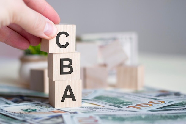 CBA テキスト費用便益分析ビジネス コンセプトを持つ木製キューブ ブロックを持っている手