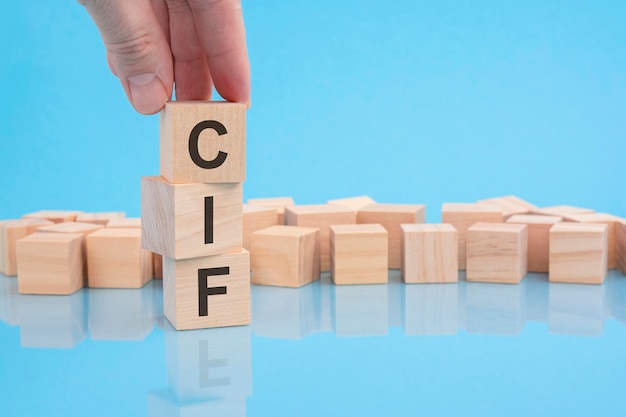 Рука держит деревянный кубический блок с текстовой финансовой и бизнес-концепцией CIF