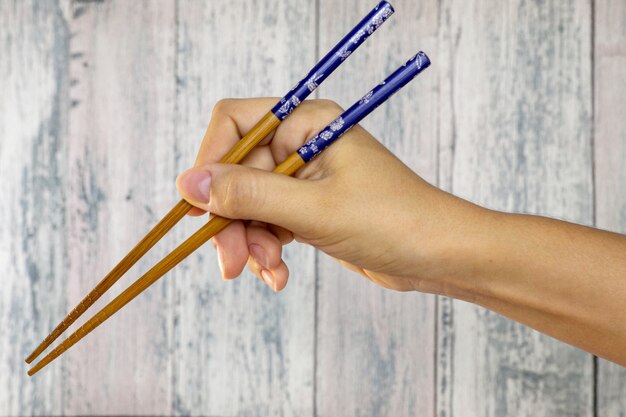 Hand holding wooden chopstick utensil for eating oriental food