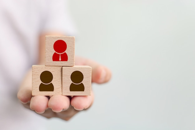 Photo hand holding wooden cube block on top pyramid with human icon